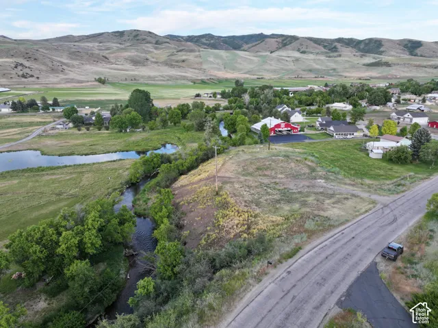 Expansive rural landscape featuring a winding waterway, distant mountains, and scattered residential properties