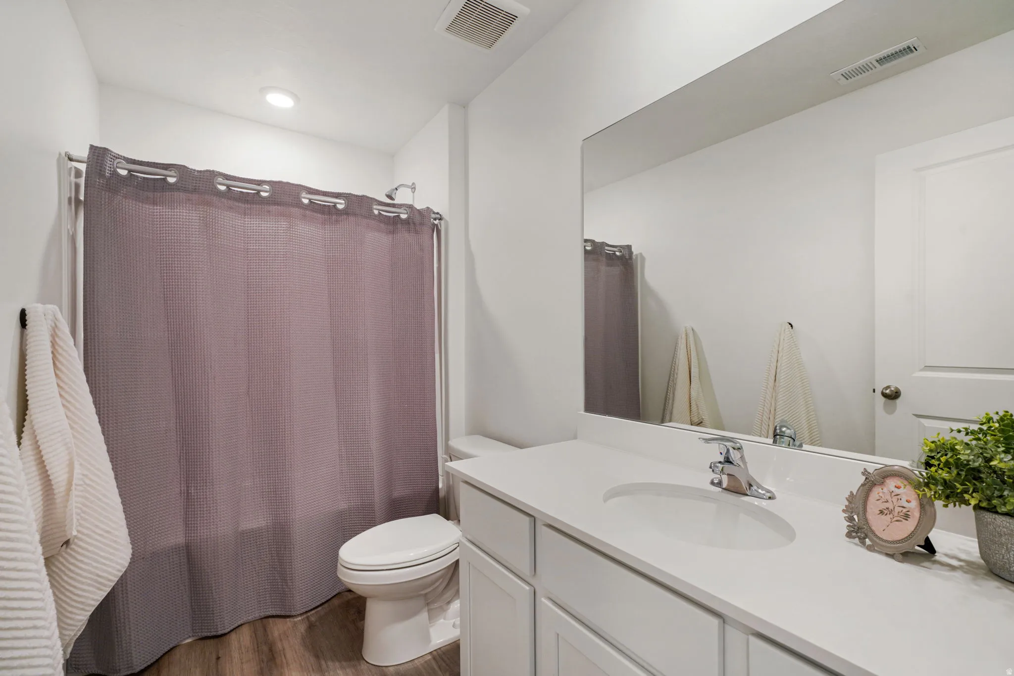 Bathroom featuring a white vanity with an integrated sink, chrome faucet, and a large wall-mounted mirror