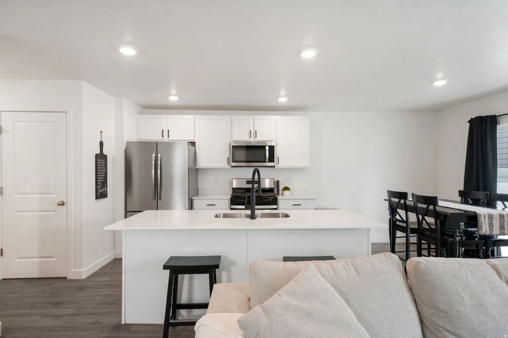 Kitchen featuring stainless steel appliances, white cabinetry, a large kitchen island with counter seating, and wood-finish flooring