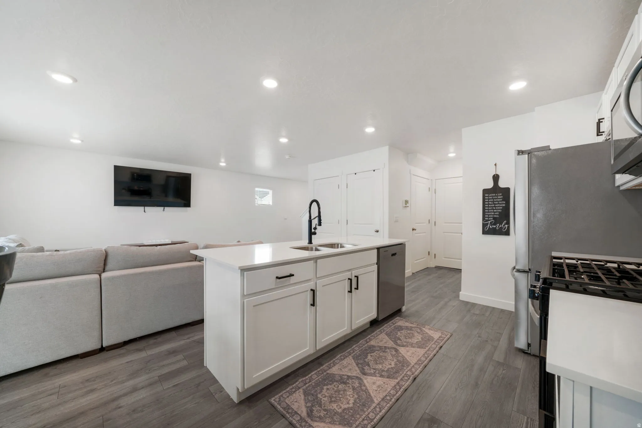 Kitchen island with white cabinetry, black hardware, and integrated sink