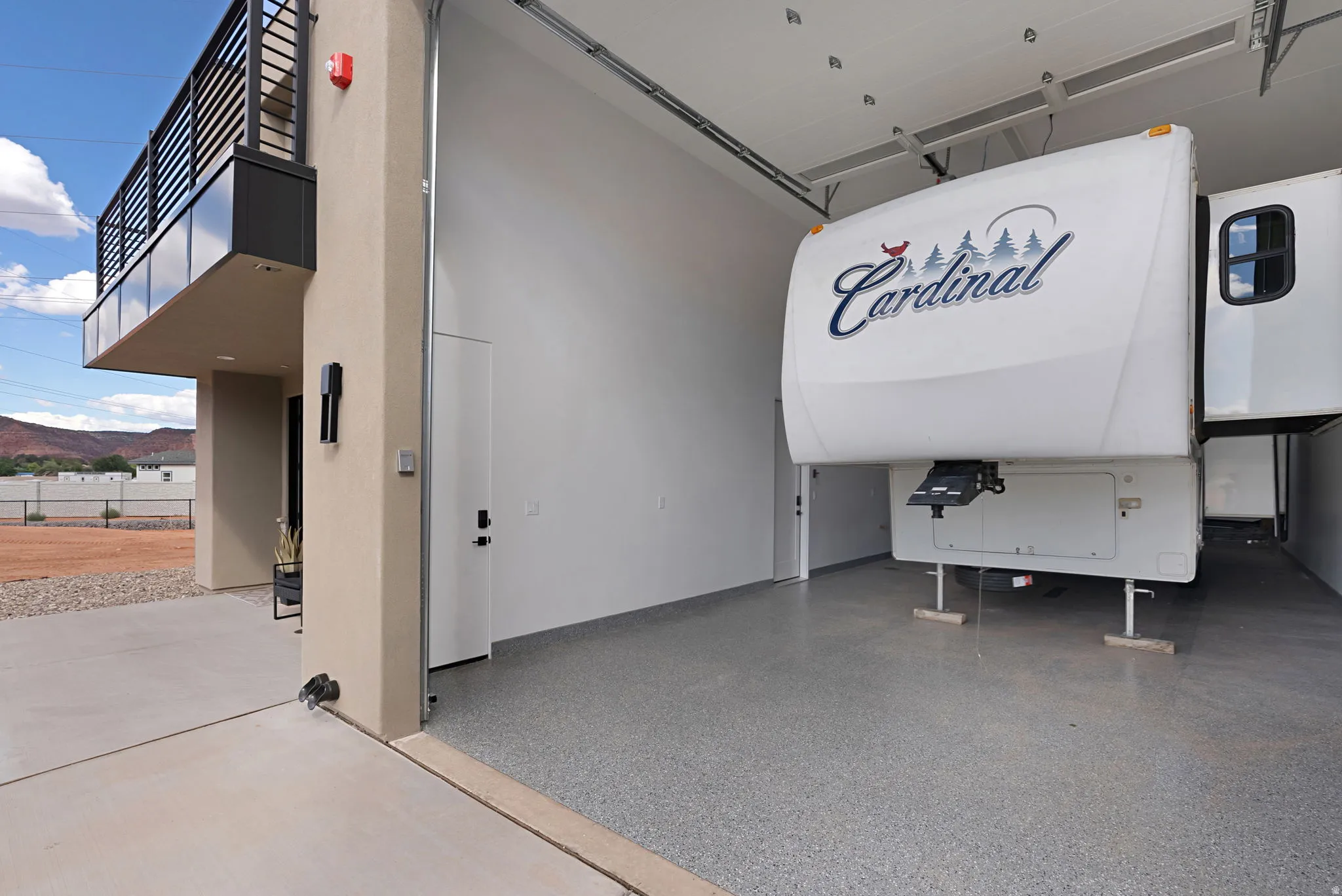 Spacious garage with an epoxy-coated concrete floor, high ceilings, and a large roll-up door