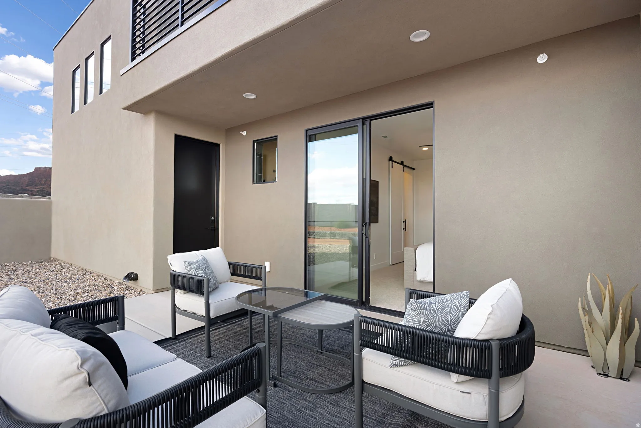Outdoor patio with sliding glass doors, smooth stucco exterior, and integrated overhead lighting