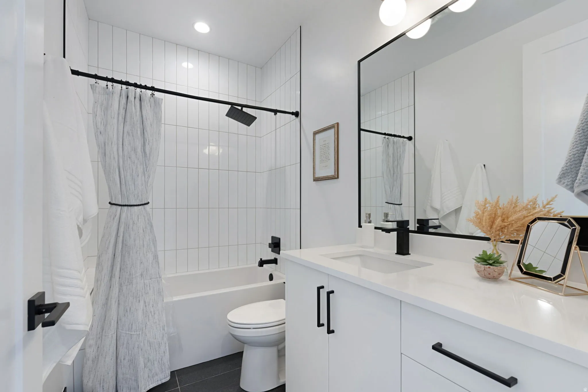 White subway tile shower surround with a tub/shower combination, black matte shower fixtures, and a toilet