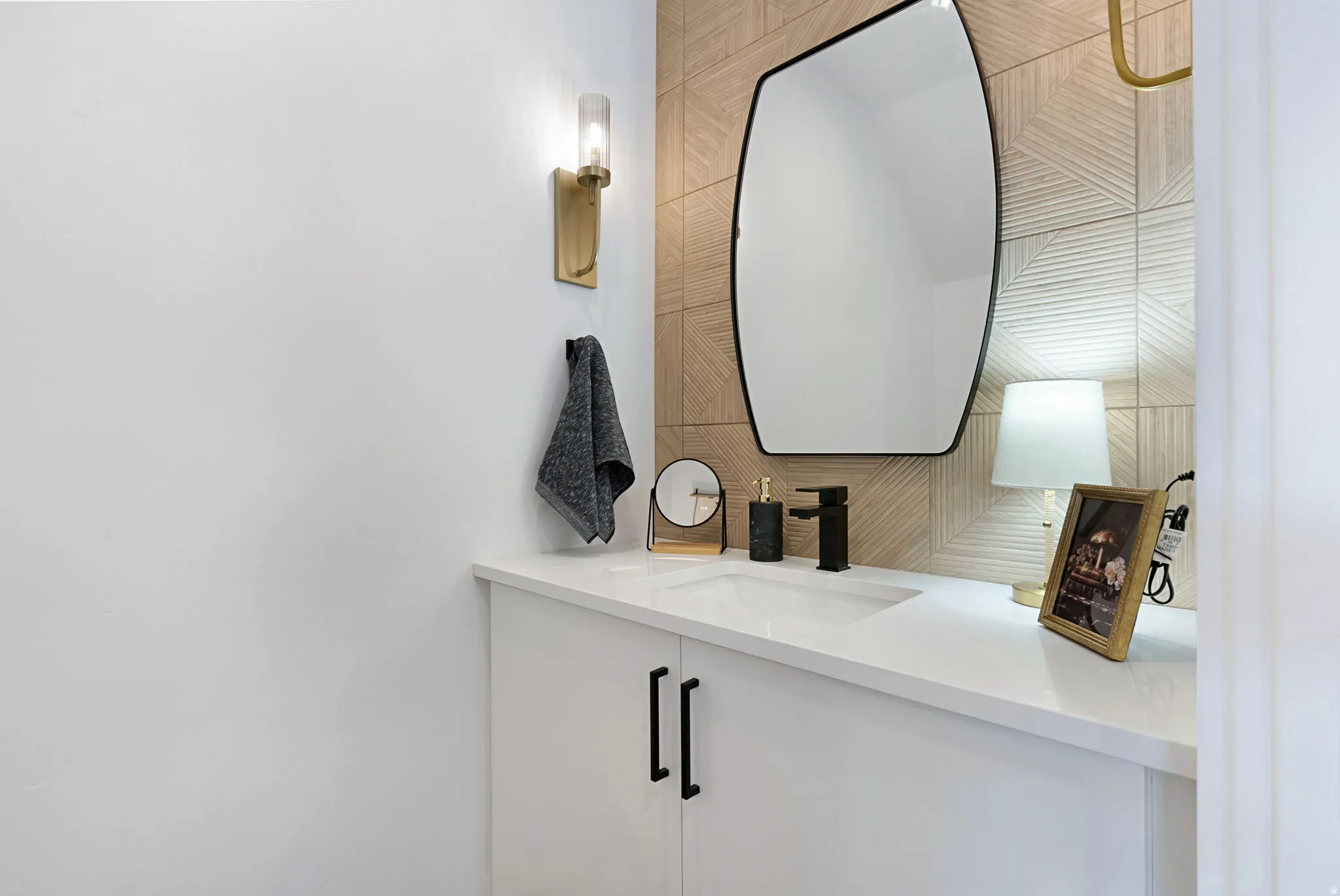 White vanity with black cabinet pulls, white countertop, integrated sink, and matte black faucet