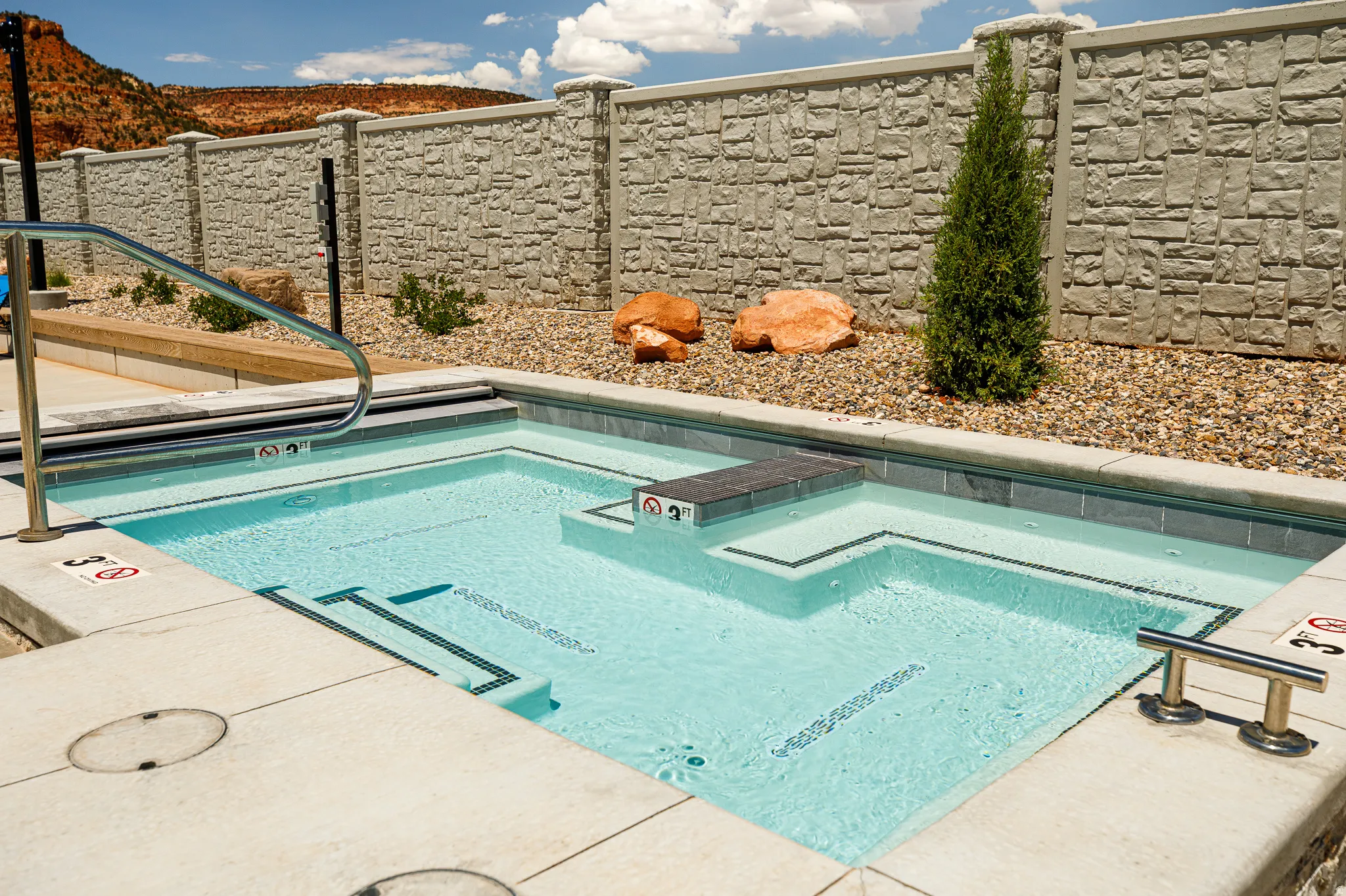 Structured pool with integrated steps, stainless steel handrails, and surrounding concrete decking