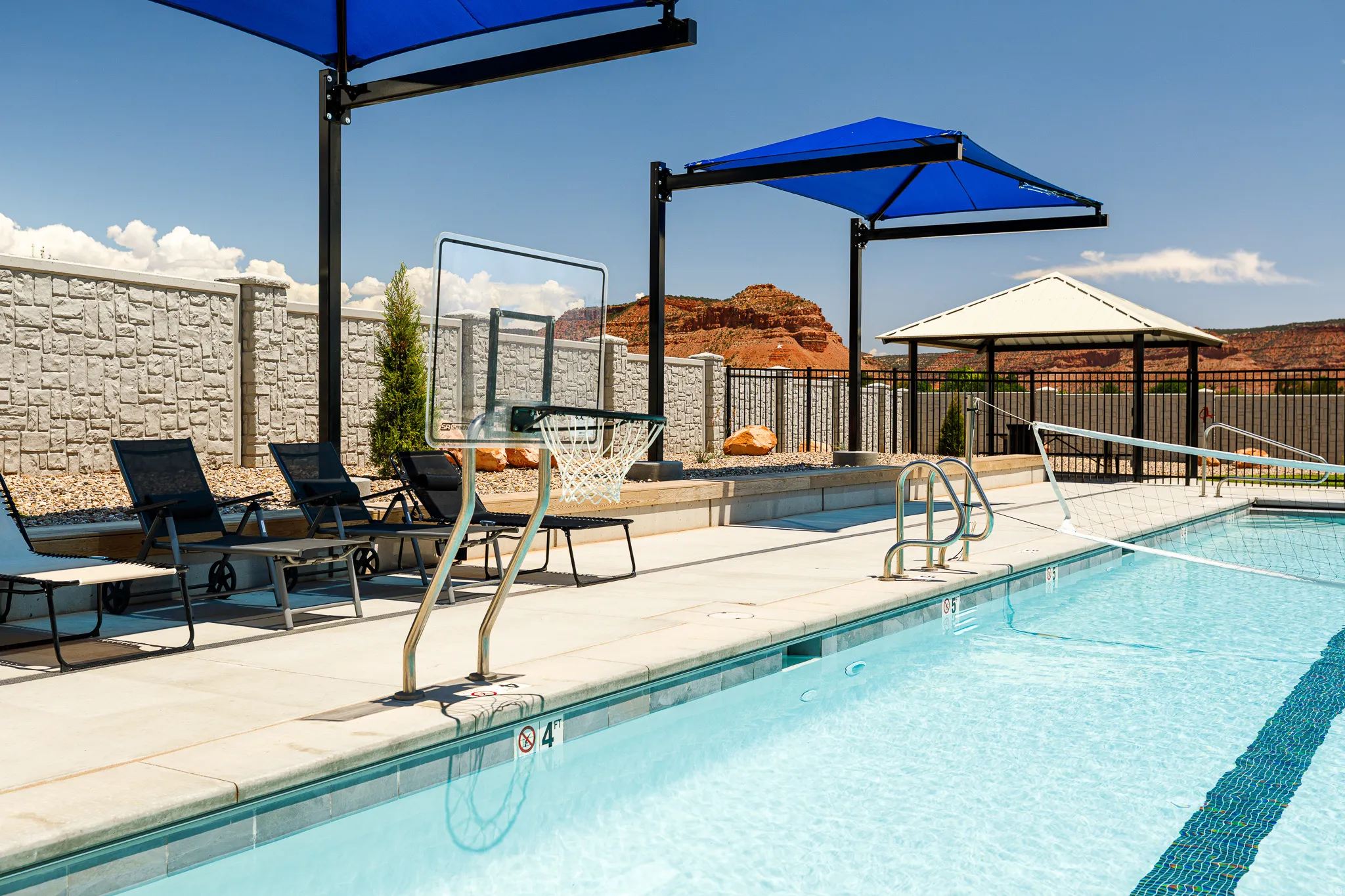 Outdoor swimming pool with integrated basketball hoop, poolside lounge chairs, and a shaded pergola structure