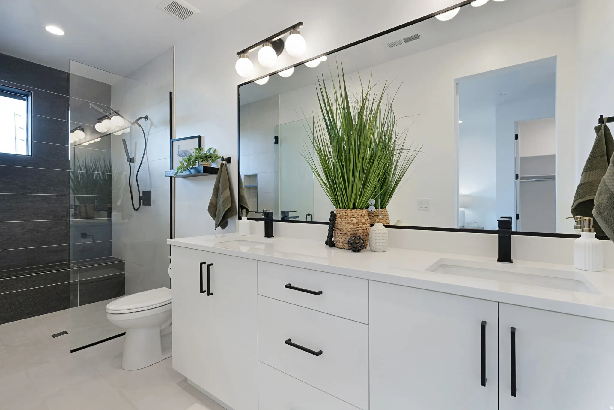 Dual vanity with white cabinetry, matte black hardware, and an expansive mirror