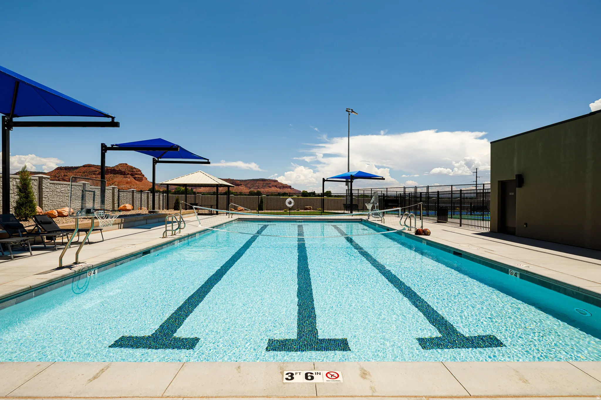 Outdoor lap pool with integrated steps, multiple shade structures, and surrounding hardscaping