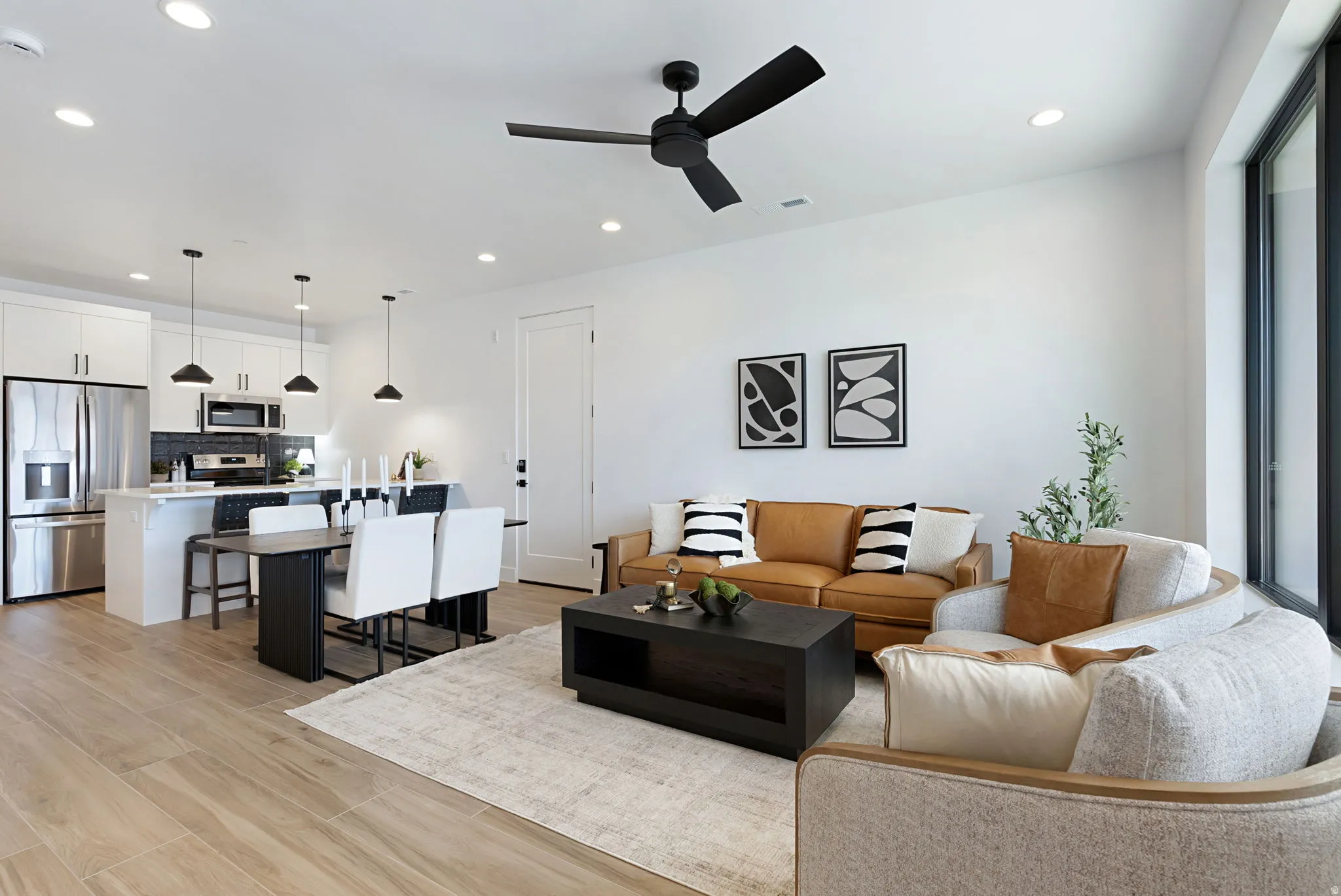 Open-concept living area with wood-finish flooring, recessed lighting, and a black ceiling fan