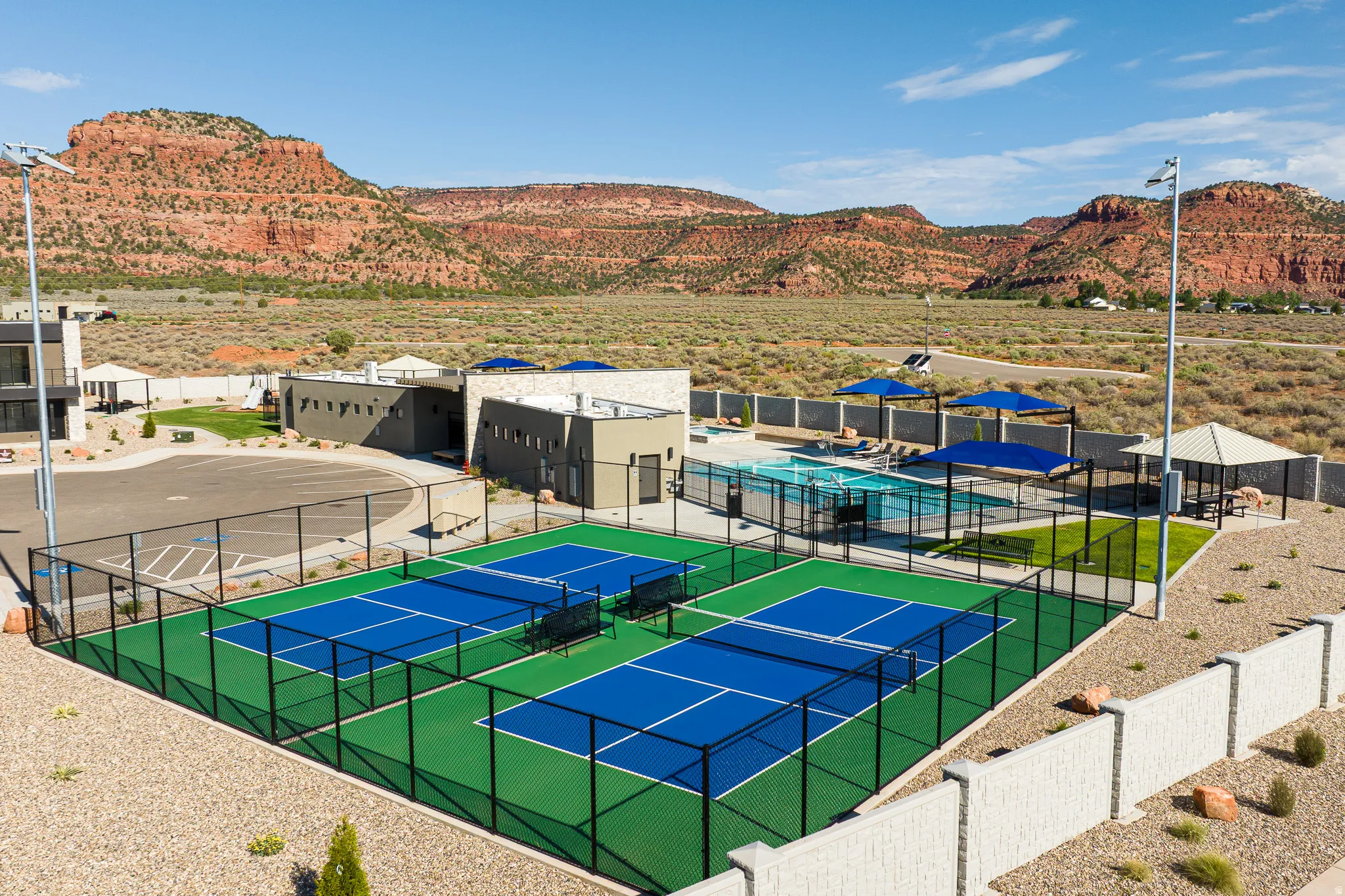 Community amenities featuring two pickleball courts, a fenced swimming pool area, a shaded gazebo, and a modern clubhouse building