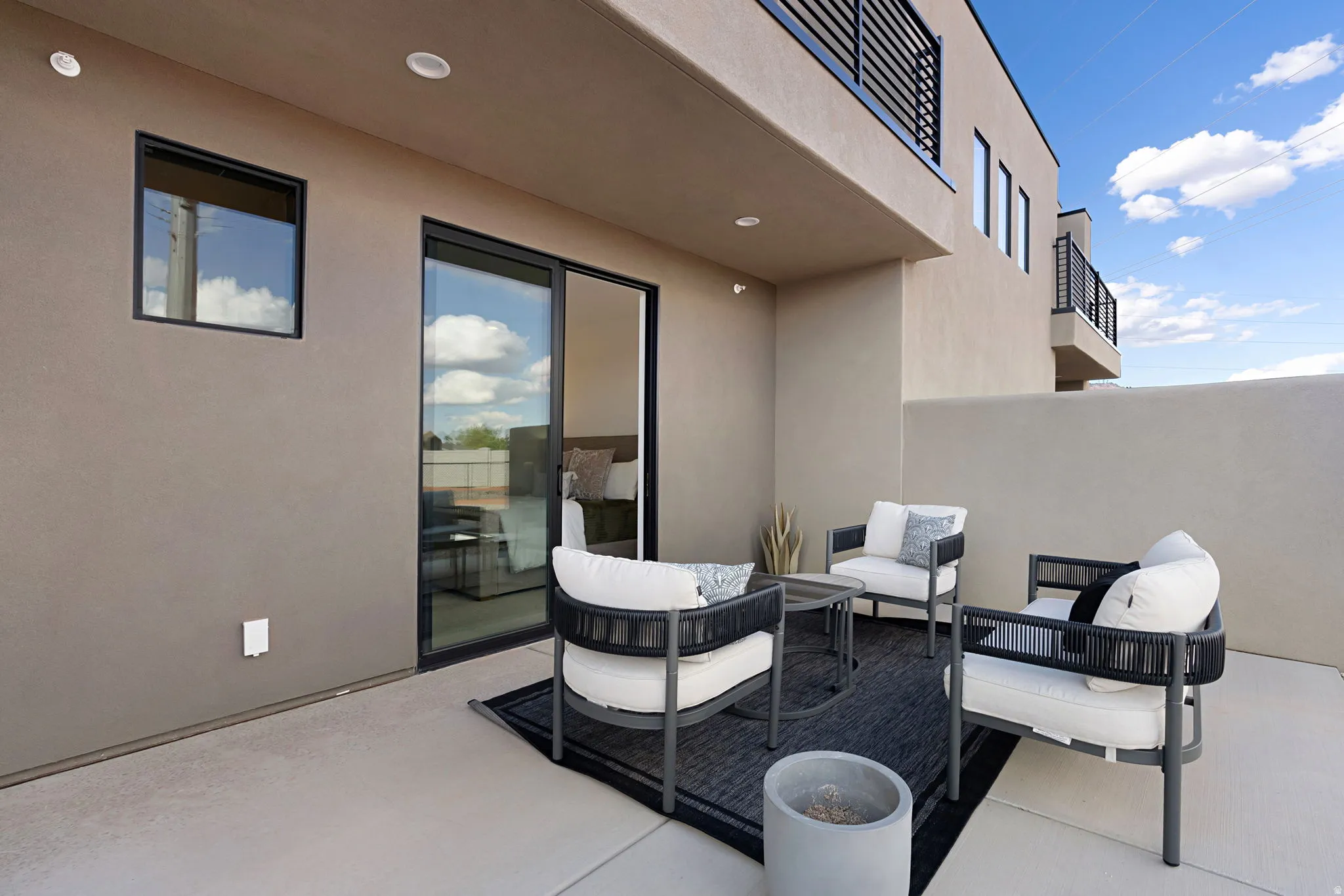 Private outdoor patio with a concrete surface, featuring a sliding glass door and recessed lighting