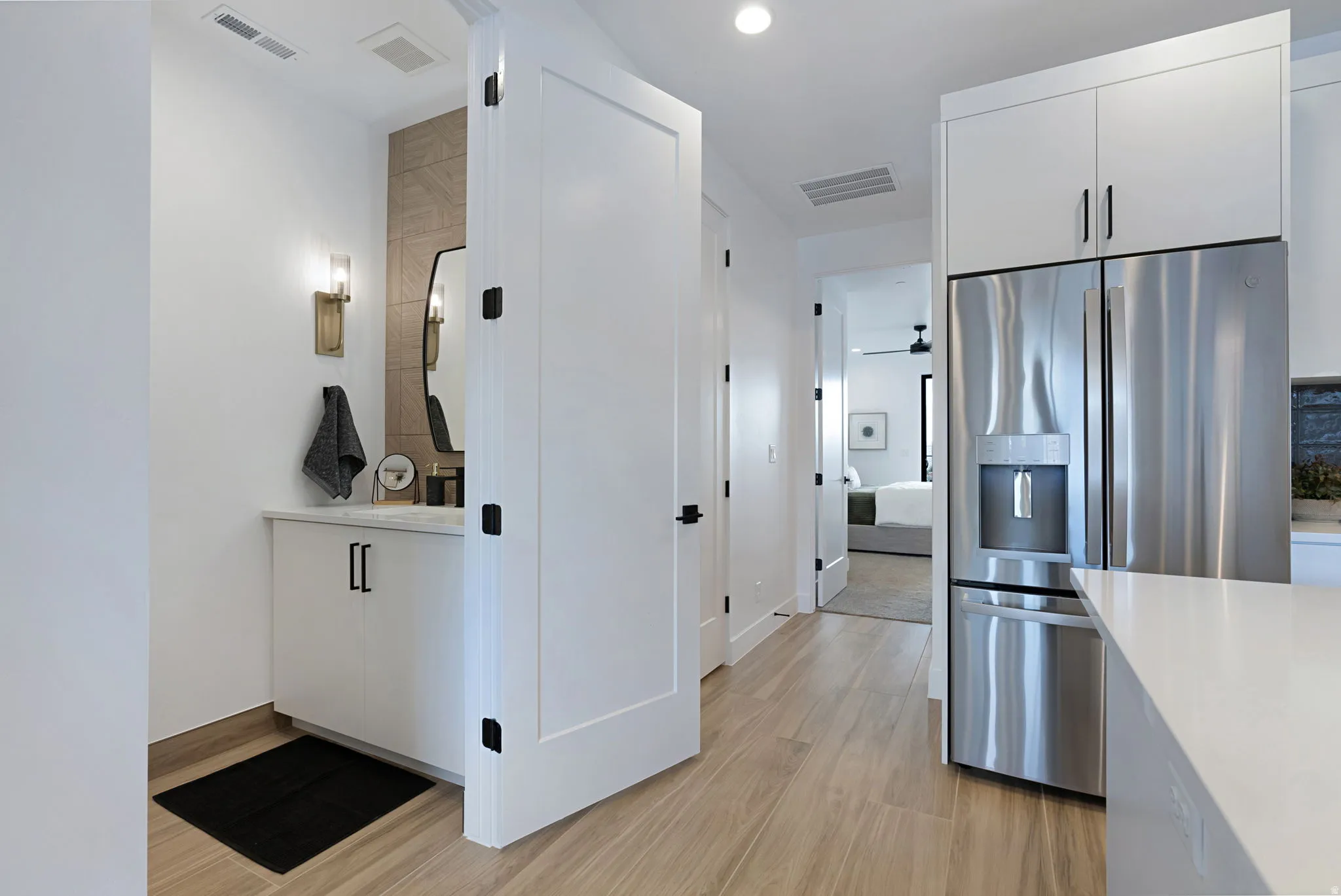 Wood-finish flooring throughout, bright white walls, and a modern white vanity with a rectangular basin