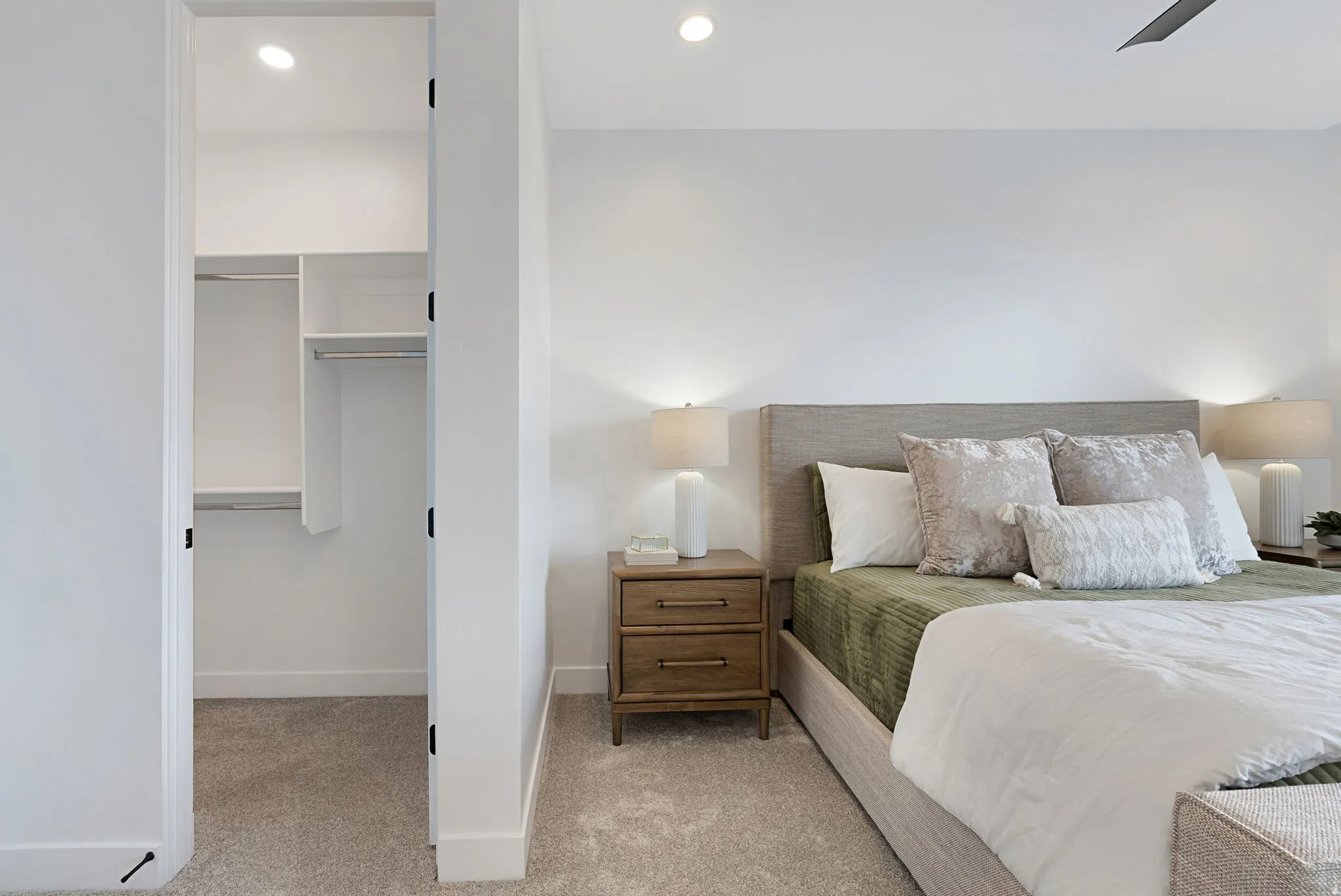 Recessed lighting, ceiling fan, built-in closet organization system, plush carpet, and light wood-finish nightstands