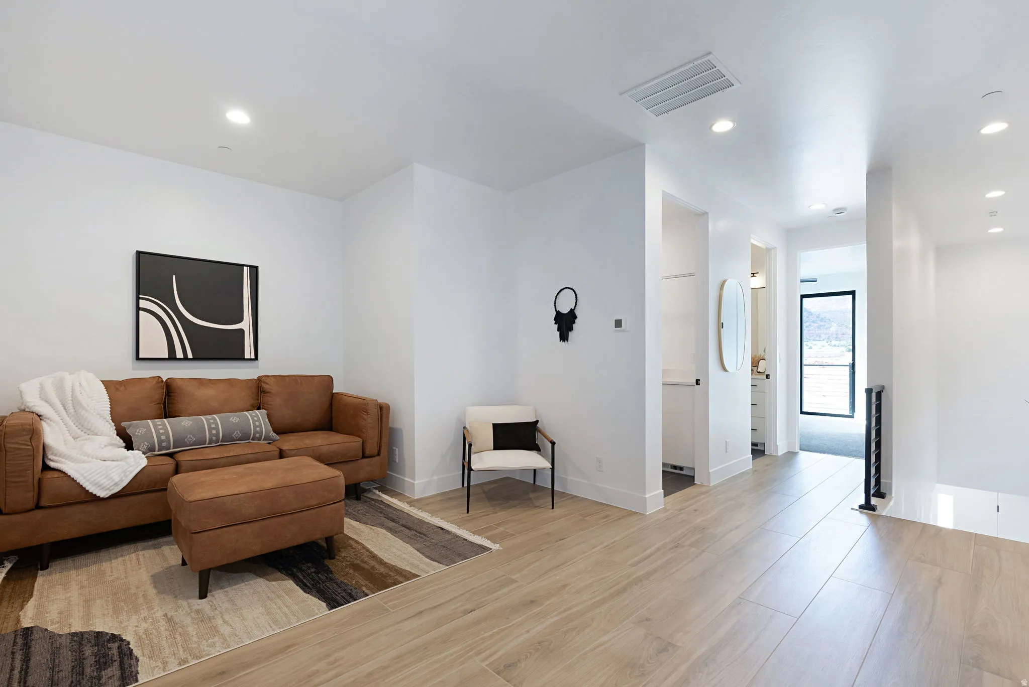 Recessed lighting, wood-finish flooring, white walls, black metal railing, and contemporary light fixtures