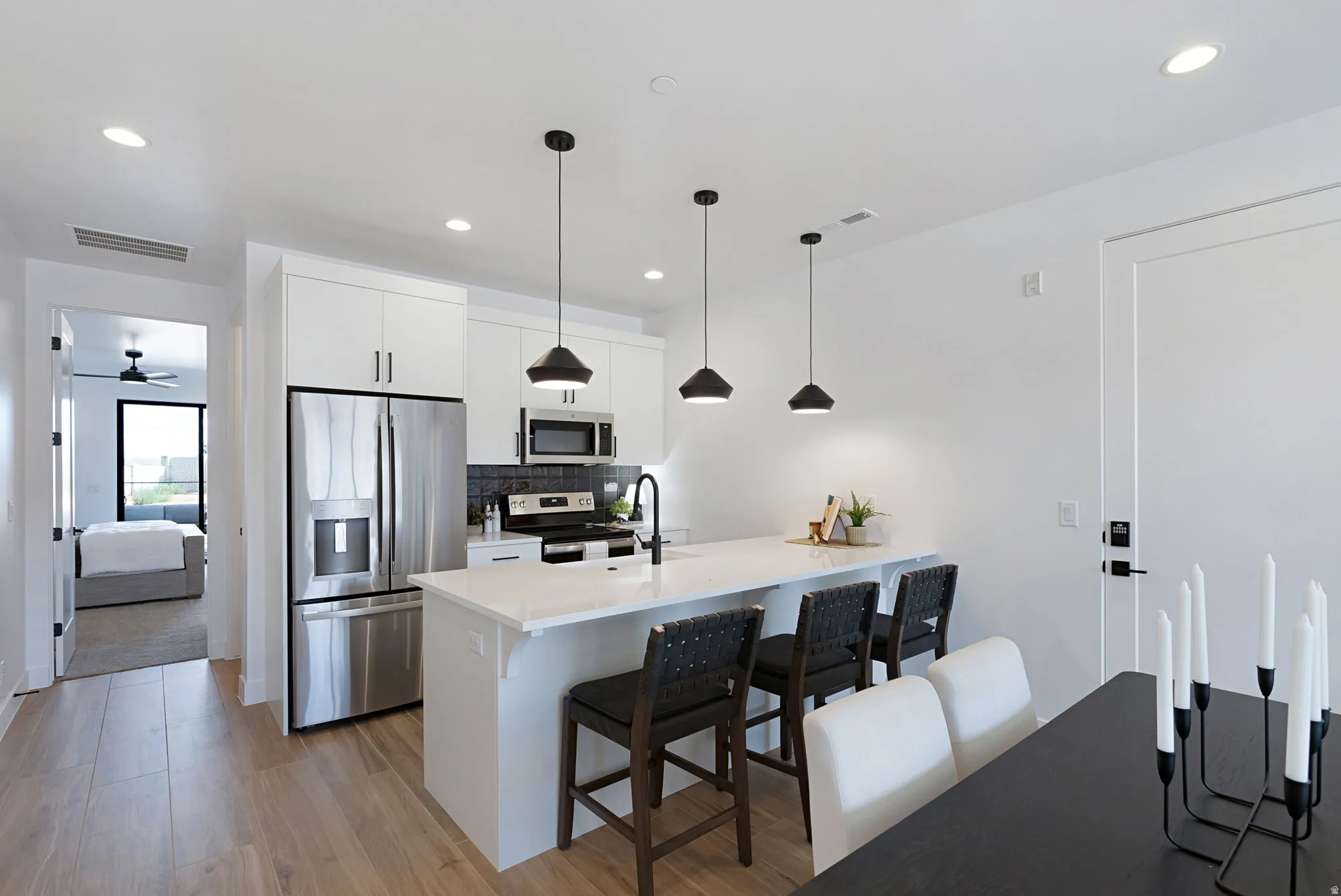 Modern kitchen featuring stainless steel appliances, white cabinetry, a large island with seating, and light wood-finish flooring