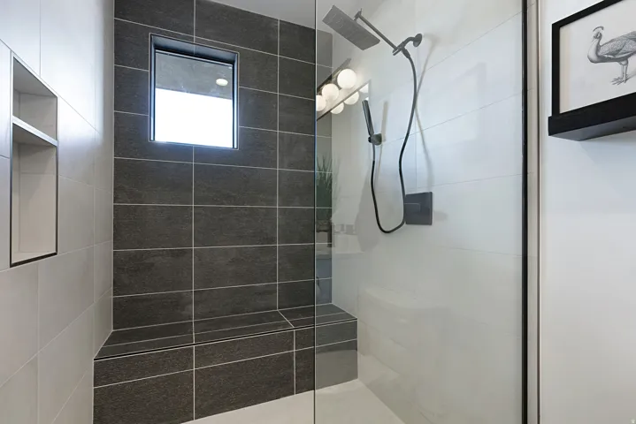 Tiled shower with a built-in bench, recessed window, and matte black dual shower heads