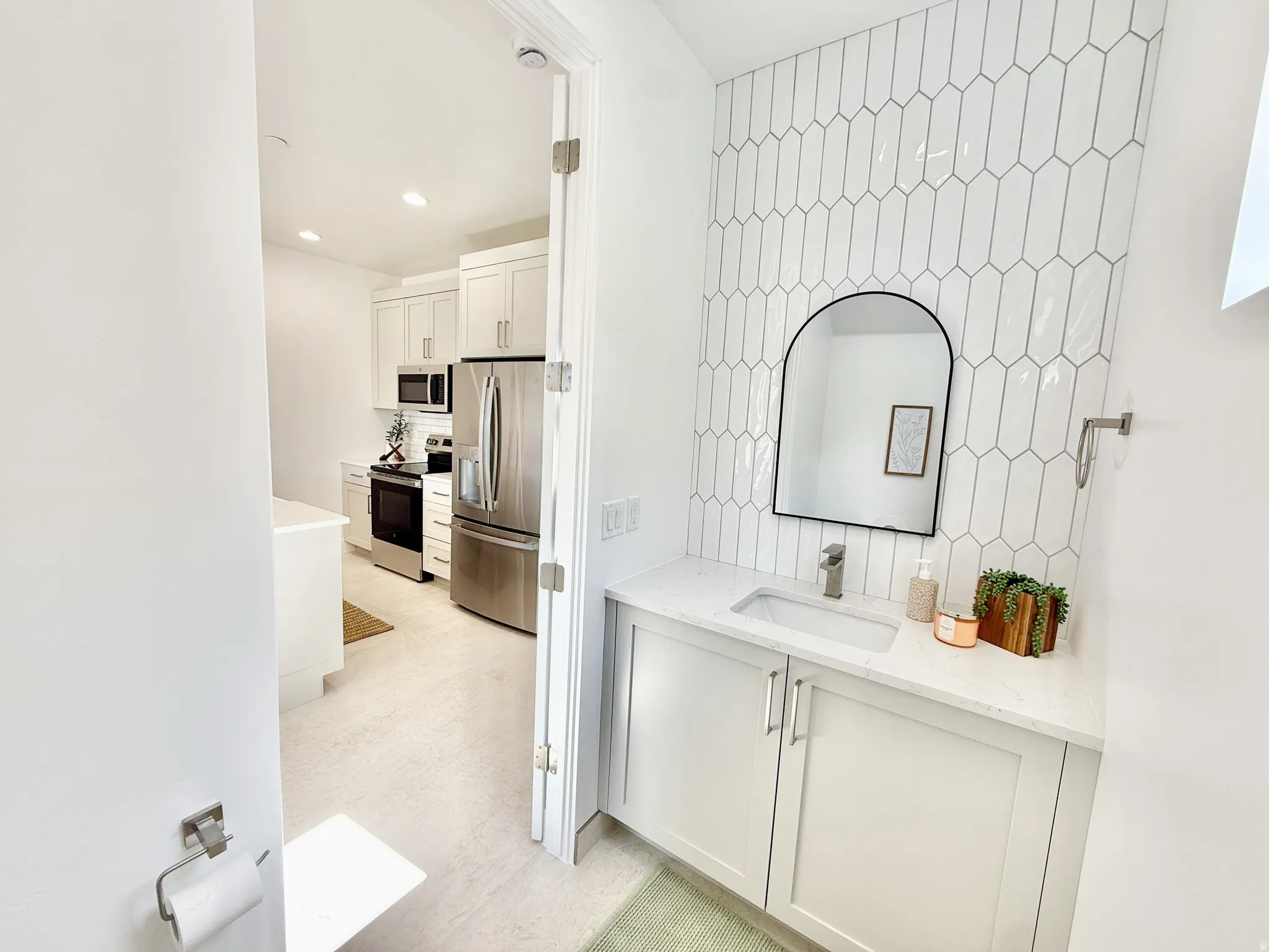 Powder room with a contemporary vanity, integrated sink, and an arched mirror