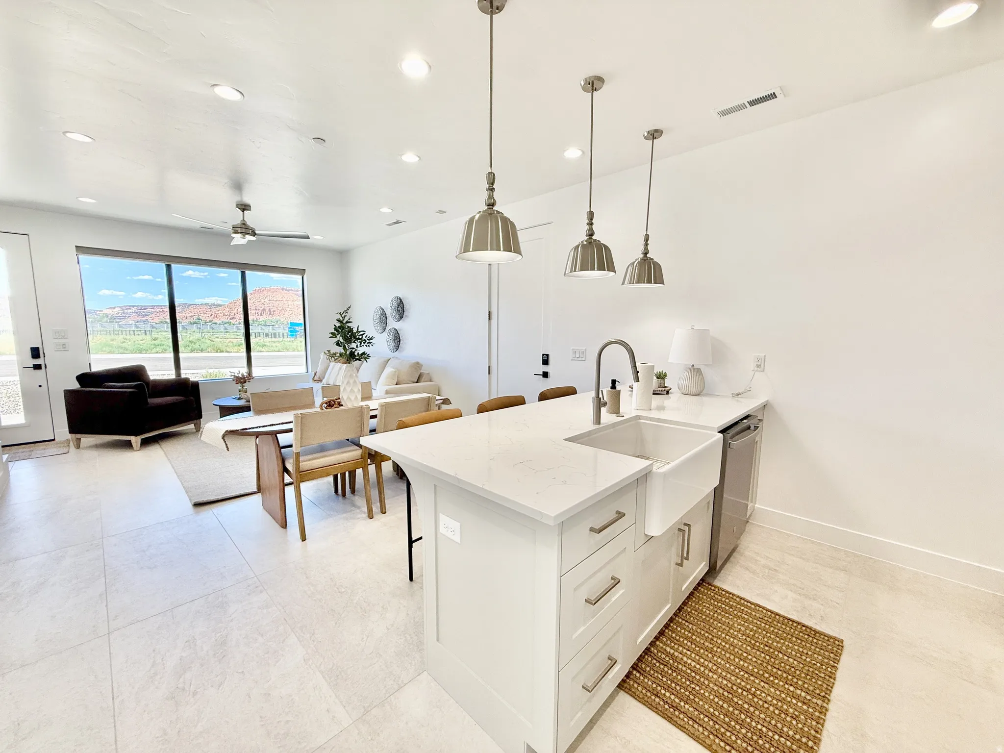 Open-concept living area featuring a kitchen island with a farmhouse sink, stainless steel appliances, recessed lighting, and large windows