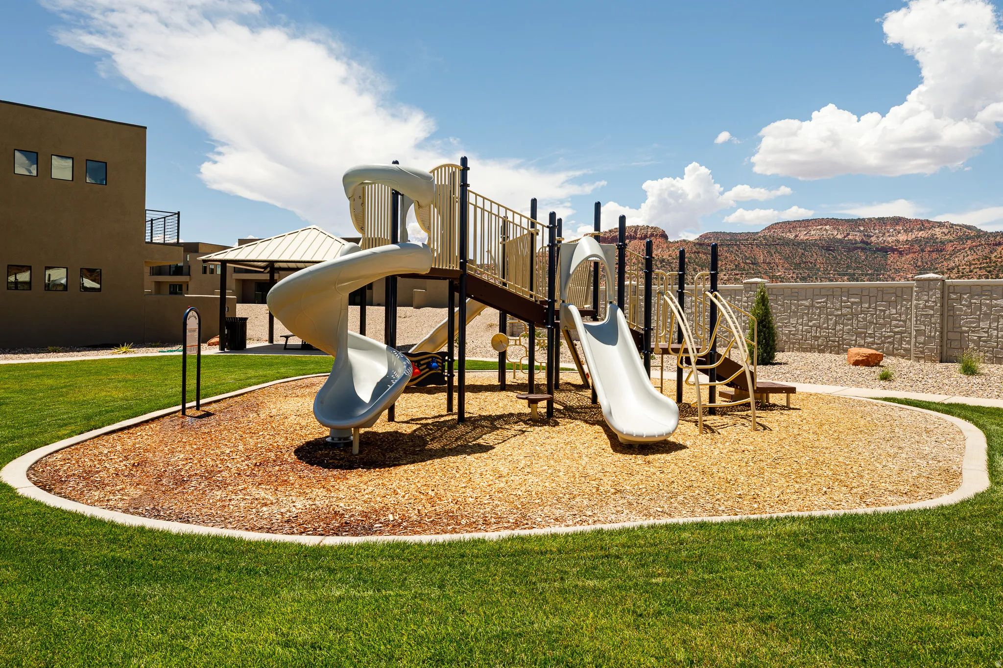 Recreational playground featuring two slides, a climbing structure, and wood chip surfacing