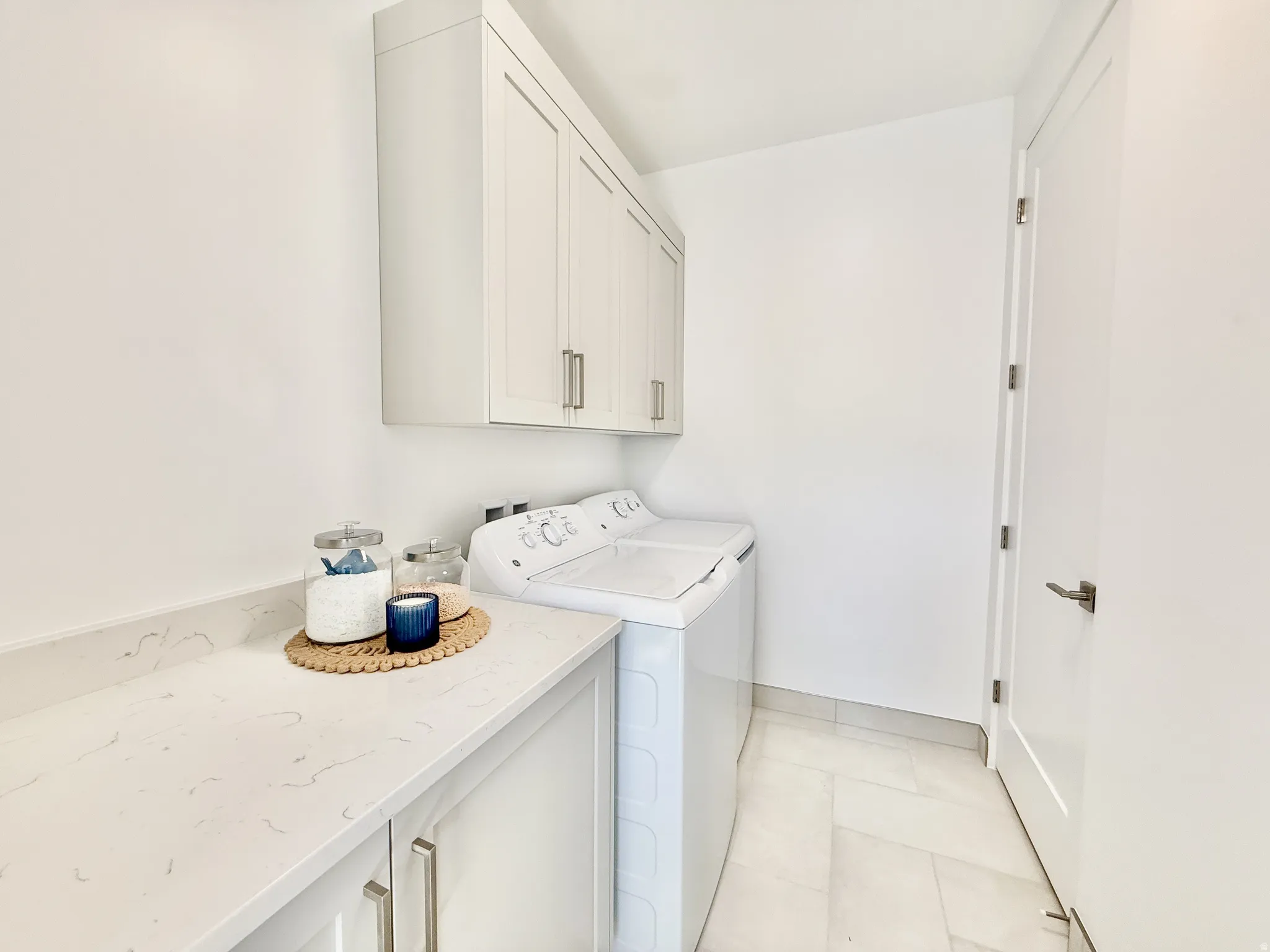 White shaker-style cabinetry, light-toned countertop, and light-toned floor tile