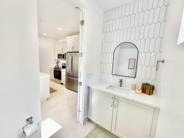 Powder room with a contemporary vanity, integrated sink, and an arched mirror