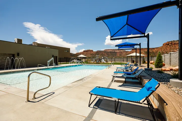 Community swimming pool with water features, concrete decking, and multiple shade structures