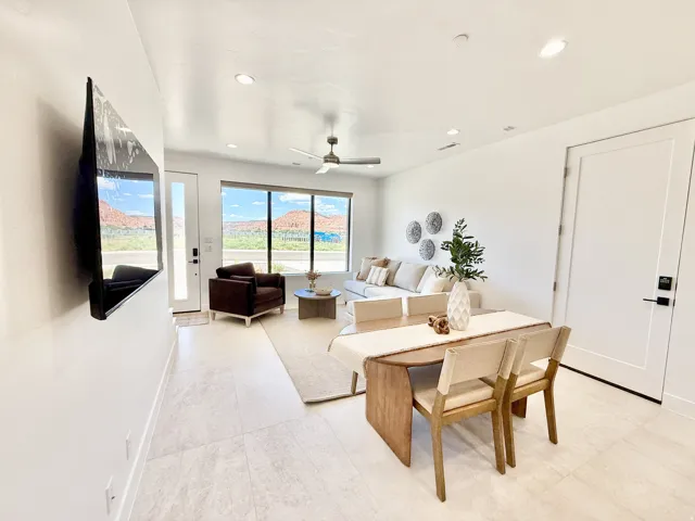 Open-concept living space featuring high ceilings, recessed lighting, expansive windows, light-toned tile flooring, and a ceiling fan
