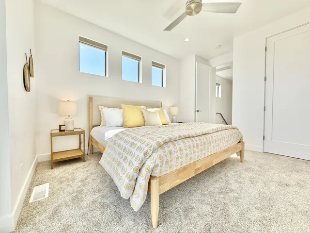 Recessed lighting, ceiling fan, three horizontal windows, and light-colored carpeting