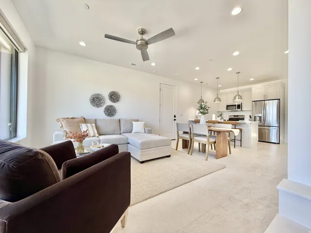 Open-concept living area featuring a ceiling fan, recessed lighting, and light-toned flooring