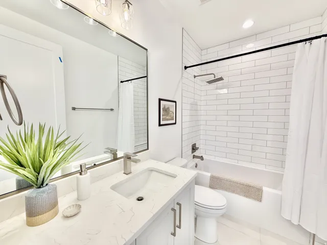 Bathroom featuring a subway-tiled shower with rainfall showerhead, full bathtub, vanity with an integrated sink and brushed nickel faucet, and a large wall-mounted mirror