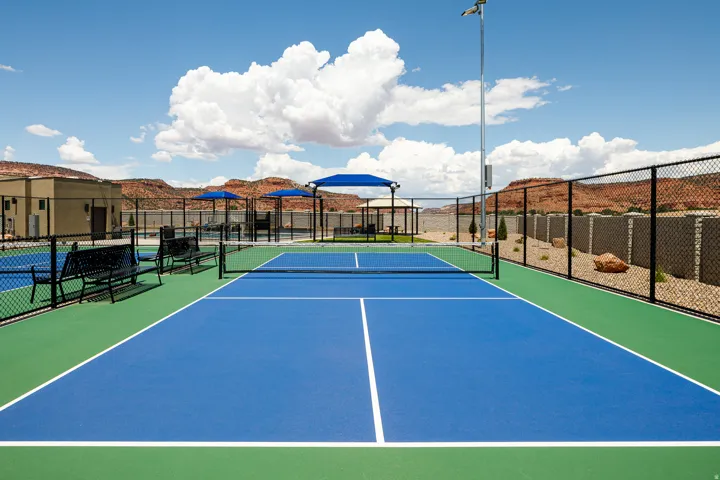 Blue and green outdoor sports court with a dark chain-link fence