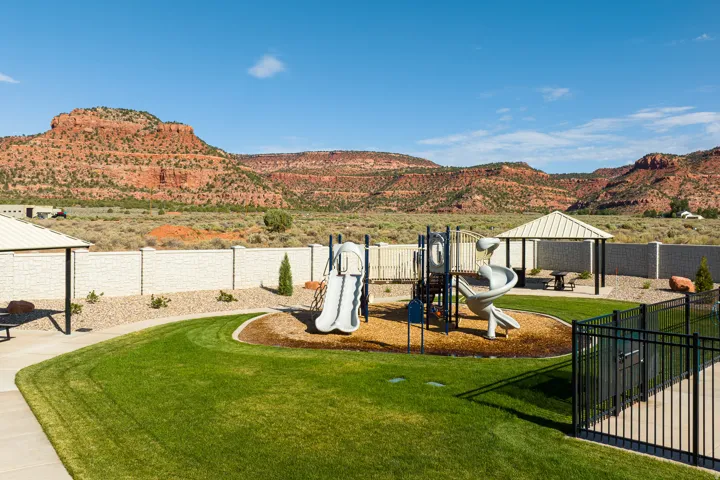 Expansive green lawn with a dedicated playground area, shaded picnic gazebo, and a perimeter privacy wall