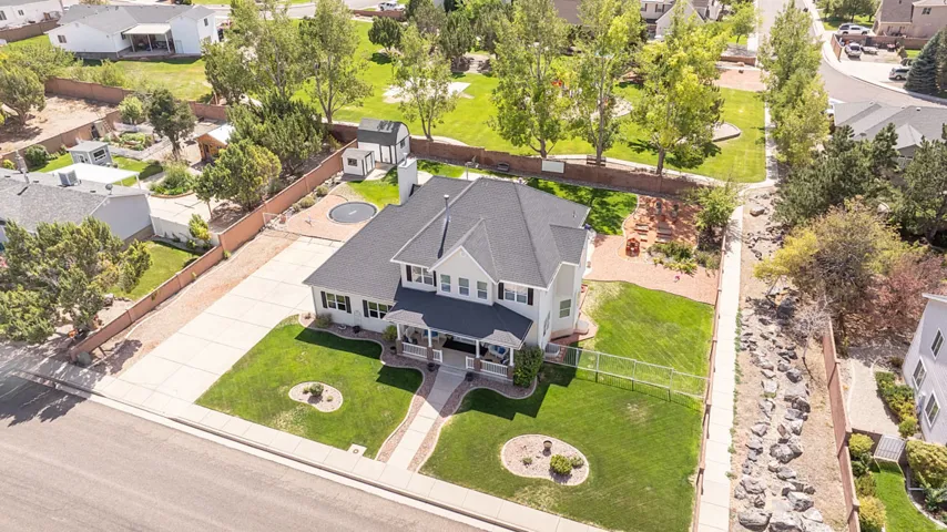 Gabled roofline, front porch, concrete driveway, fenced yard, and a separate storage shed