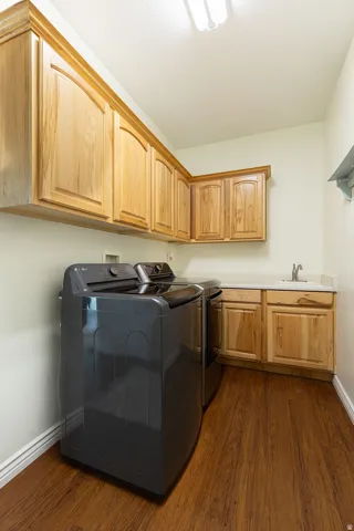 Wood-finish flooring, light wood cabinetry, built-in sink with countertop, and overhead lighting