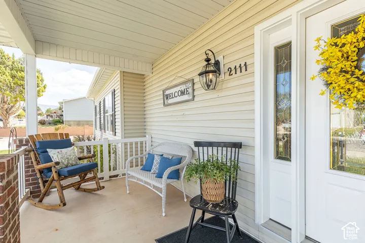 Covered porch with white railings, brick pillar, and exterior siding