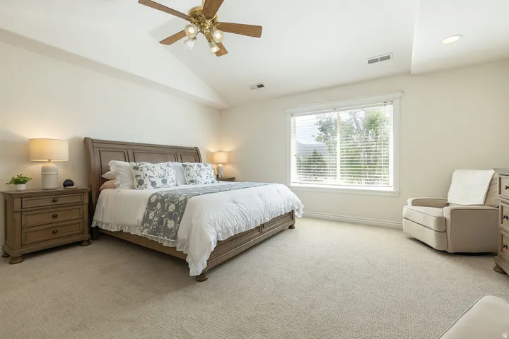 Vaulted ceiling with a ceiling fan, recessed lighting, carpet flooring, large window, and a wood-finish bed frame