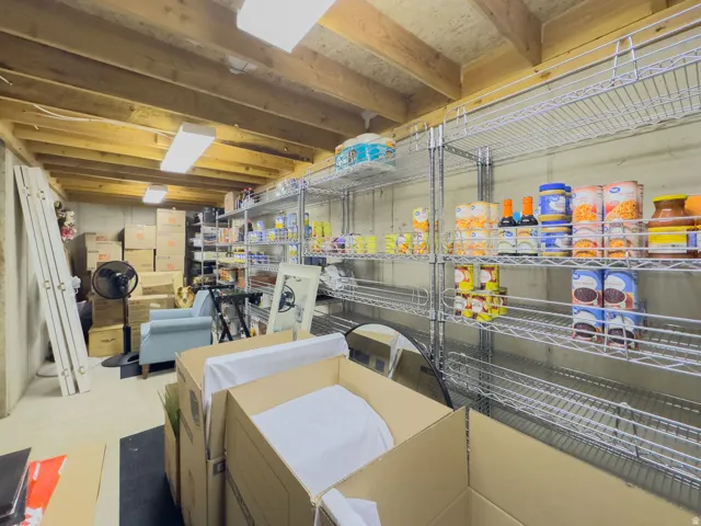 Unfinished lower level featuring exposed wood beam ceiling, concrete walls, and overhead fluorescent lighting