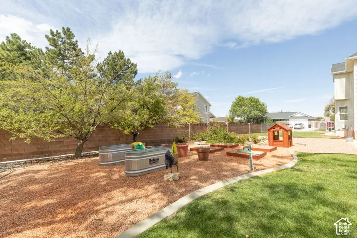 Expansive backyard featuring a manicured lawn, established trees, and a brick privacy fence