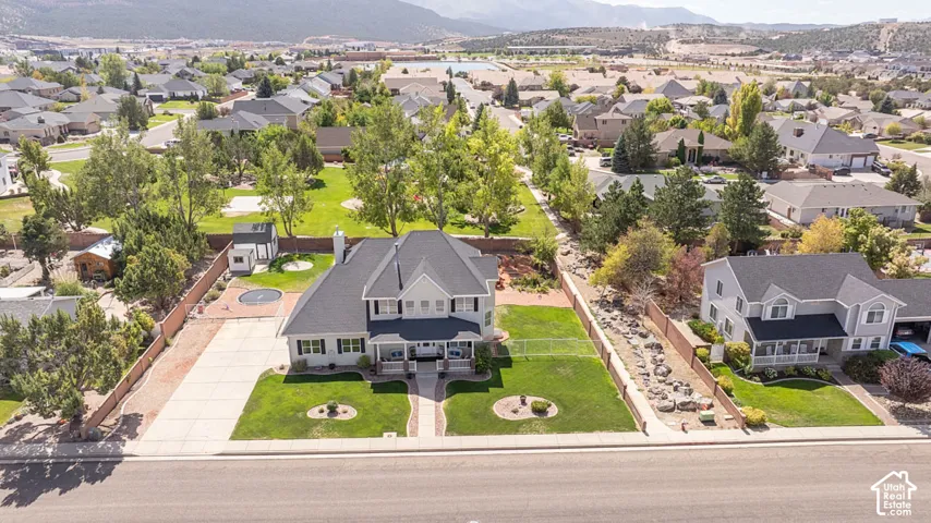 Two-story residence with a front porch, an expansive paved driveway, and a fenced backyard
