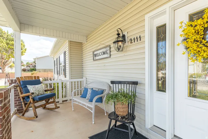 Covered porch with white railings, brick pillar, and exterior siding