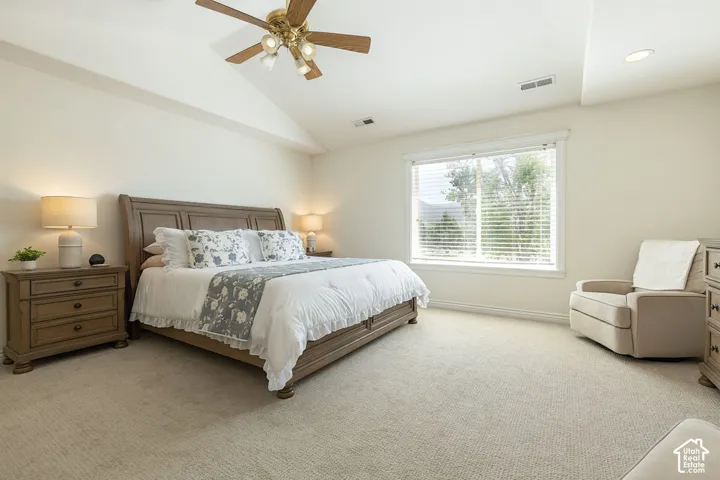Vaulted ceiling with a ceiling fan, recessed lighting, carpet flooring, large window, and a wood-finish bed frame