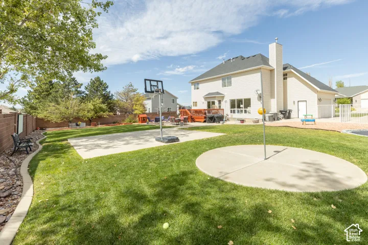 Expansive backyard featuring a lush lawn, concrete sport court, and a separate circular concrete patio