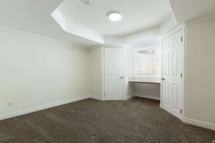 Recessed lighting, built-in desk, paneled doors, and crown molding