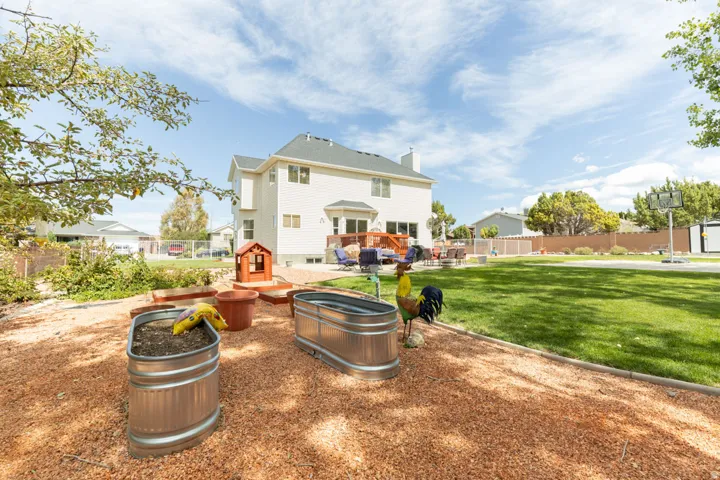 Expansive backyard featuring a manicured lawn, a raised deck, and a dedicated garden area with galvanized planters
