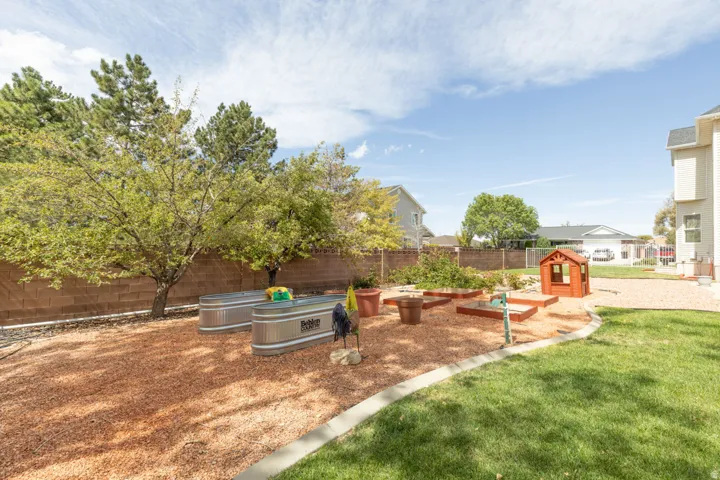 Expansive backyard featuring a manicured lawn, established trees, and a brick privacy fence