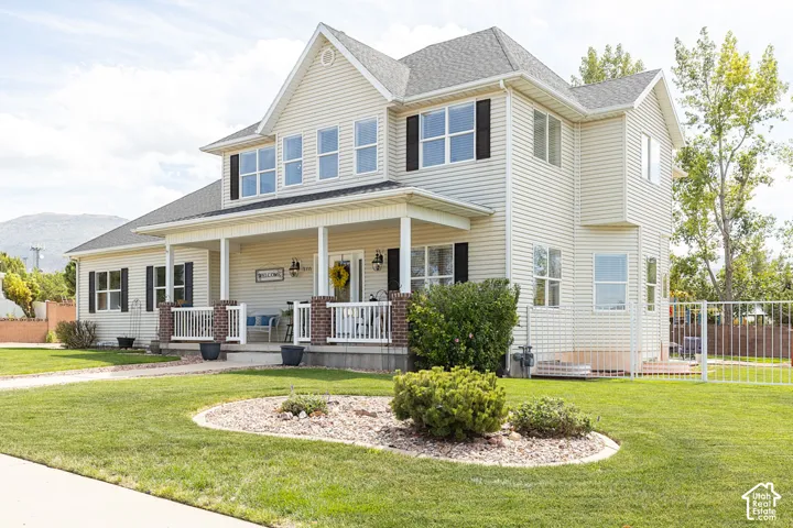 Two-story property featuring a covered front porch, white railing, and decorative brick pillars