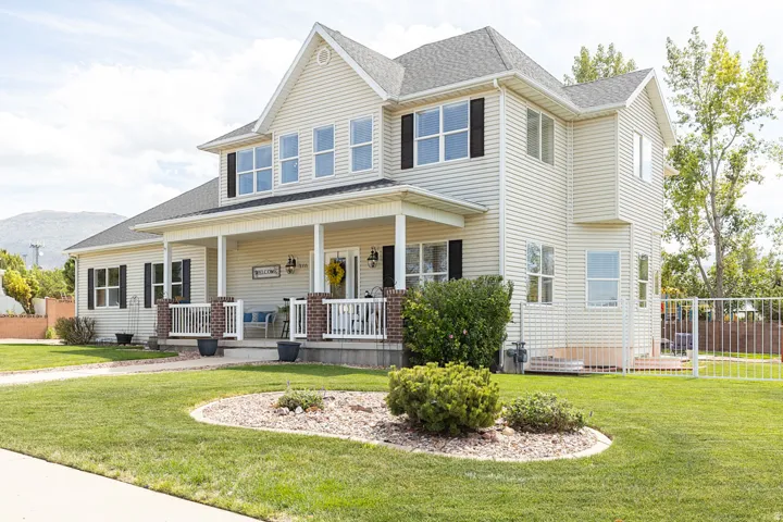 Two-story property featuring a covered front porch, white railing, and decorative brick pillars