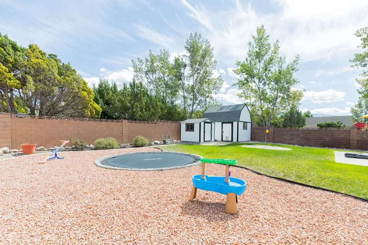 Expansive backyard featuring a partial grass lawn, a partial bark-covered area, and a storage shed