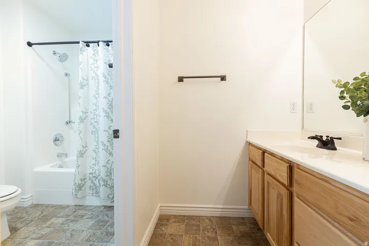 Light wood-finish vanity with white countertop, integrated sink, and dark bronze faucet
