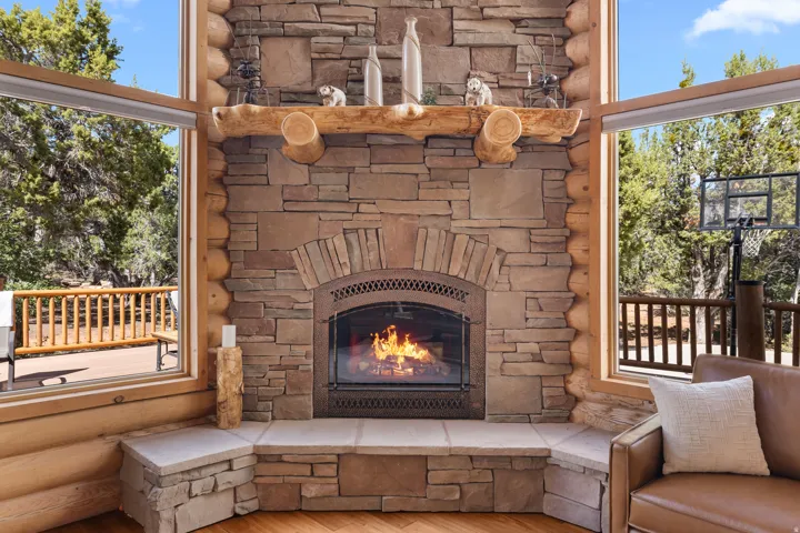 Stone-clad fireplace with an arched firebox and a natural wood mantel